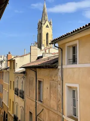 a living room with a couch and a kitchen at Mazarin Suite Centre ville historique proche cours Mirabeau in Aix-en-Provence