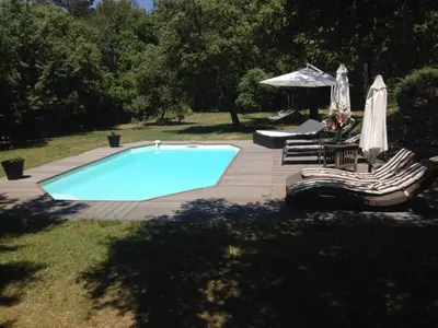 a swimming pool with two chairs and an umbrella at Villa provençale entre Aix en Provence et Luberon in Rognes