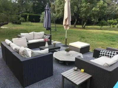 a patio with couches and tables and an umbrella at Villa provençale entre Aix en Provence et Luberon in Rognes
