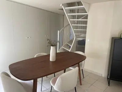 a dining room table with white chairs and a staircase at UN DOUX MOMENT in Pernes-les-Fontaines