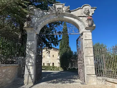 an entrance to a gate with a building in the background at Domaine Jourdan in Le Puy-Sainte-Réparade