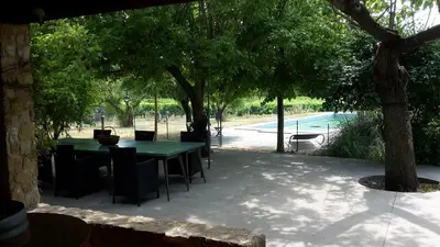 a patio with a table and chairs under trees at Maison à Ansouis Luberon in Ansouis