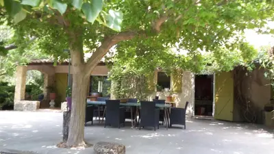 a table and chairs under a tree in a courtyard at Maison à Ansouis Luberon in Ansouis