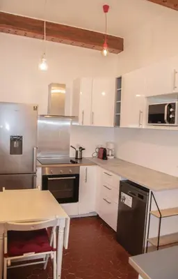 a kitchen with white cabinets and a table in it at Cosy apartment Right in Cours Mirabeau in Aix-en-Provence