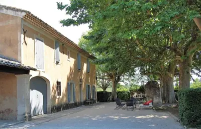 a courtyard of a house with chairs and trees at Provencal Farm with swimming pool near Isle sur la Sorgue - 10 people. in Les Vignères