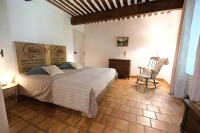 a bedroom with a large bed and a chair at Provencal Farm with swimming pool near Isle sur la Sorgue - 10 people. in Les Vignères