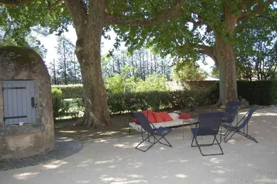 a patio with a table and chairs under a tree at Provencal Farm with swimming pool near Isle sur la Sorgue - 10 people. in Les Vignères