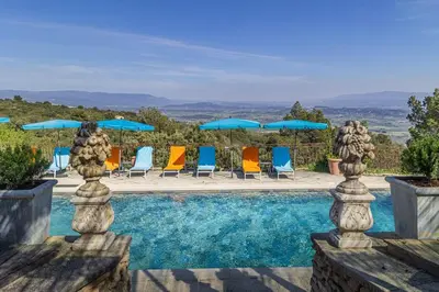 a swimming pool with chairs and umbrellas at Le Palais d'Aglaé, Hôtel de Charme in Gordes