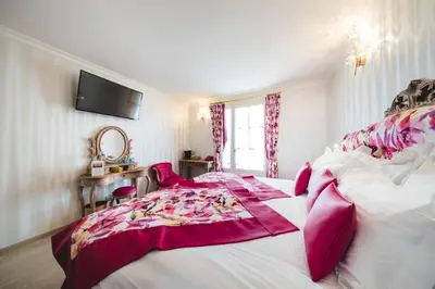 a bedroom with two beds and a tv on the wall at Le Palais d'Aglaé, Hôtel de Charme in Gordes