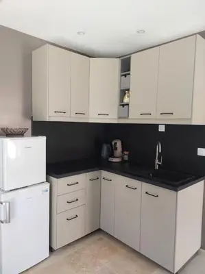 a kitchen with white cabinets and a black counter top at Location indépendante au cœur des Alpilles pour 2 personnes avec Jacuzzi in Aureille