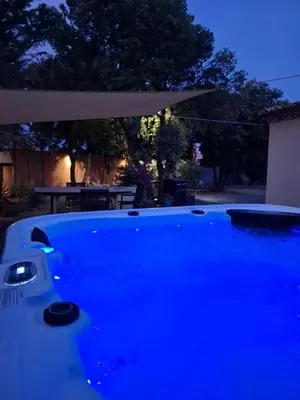 a blue swimming pool with an umbrella and a table at Location indépendante au cœur des Alpilles pour 2 personnes avec Jacuzzi in Aureille