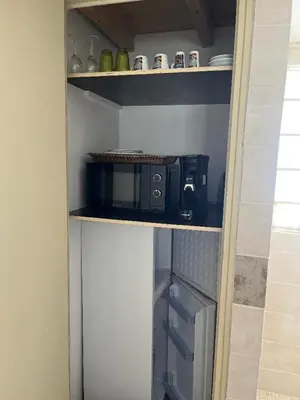 a small kitchen with a microwave on a shelf at Chambre d'hôtes in La Tour-dʼAigues