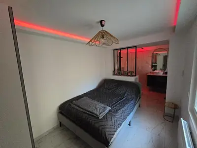 a bedroom with a bed and a bathroom with red lights at Pic chic in Châteaurenard