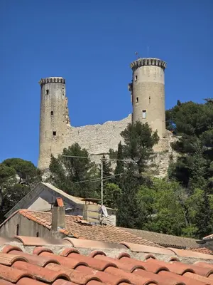 two towers on top of a hill with trees and roofs at Pic chic in Châteaurenard