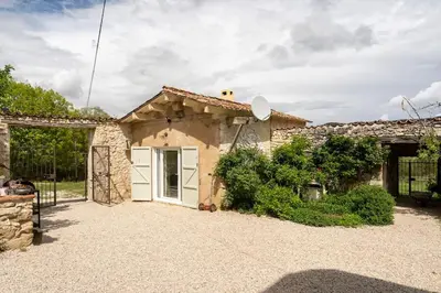 a stone house with a white door in a yard at La Grange des Davids Mas en Provence in Oppedette