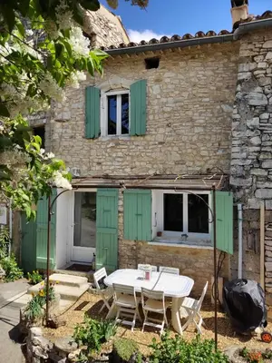 a house with green shutters and a table and chairs at Maison dans le luberon in Viens