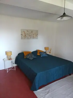 a bedroom with a blue bed with two pillows on it at Maison dans le luberon in Viens