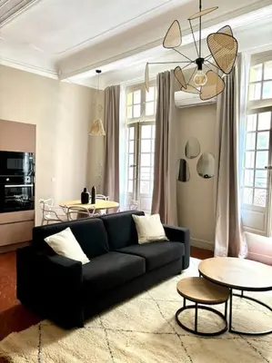 a living room with a black couch and a table at Splendide T2 au coeur d'Aix et du Cours Mirabeau in Aix-en-Provence