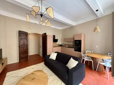 a living room with a black couch and a table at Splendide T2 au coeur d'Aix et du Cours Mirabeau in Aix-en-Provence
