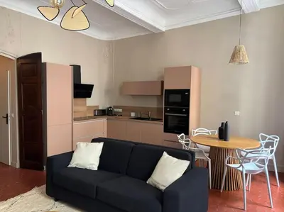 a living room with a black couch and a kitchen at Splendide T2 au coeur d'Aix et du Cours Mirabeau in Aix-en-Provence