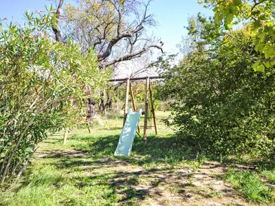 a swing set in a field with trees and grass at Holiday Home L' amandier by Interhome in Saint-Didier