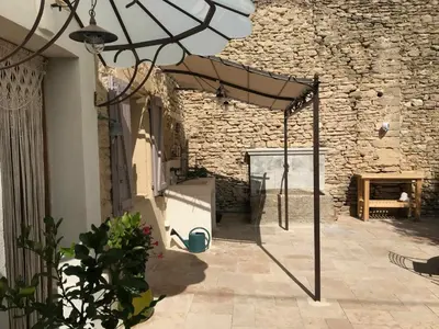 a patio with an umbrella and a stone wall at Clos de l'Abba in Gordes