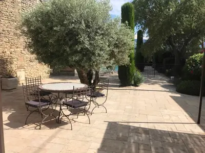 a patio with a table and chairs under a tree at Clos de l'Abba in Gordes
