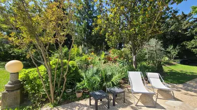 a garden with two white chairs and plants at Le Coin Retro pour séjour romantique avec piscine chauffée in Le Thor