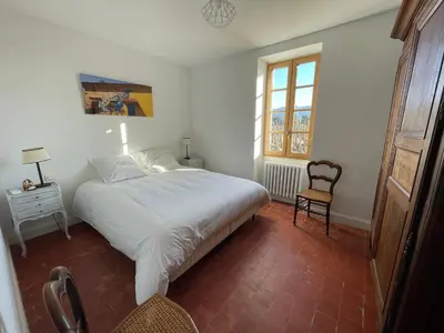 a bedroom with a large white bed and a window at Mas Chamsomat in Robion en Luberon