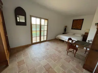 a bedroom with a bed and a table and windows at Mas Chamsomat in Robion en Luberon