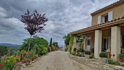 a gravel road next to a house with a tree at Le jardin des oliviers in Apt