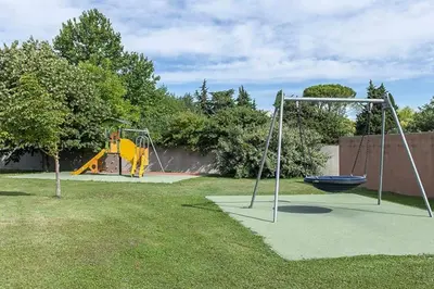 two swings in a yard with a playground at La provençale in Saint-Saturnin-lès-Avignon