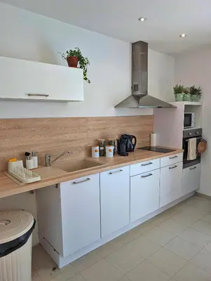 a kitchen with white cabinets and a sink at L'instant sorgue in LʼIsle-sur-la-Sorgue