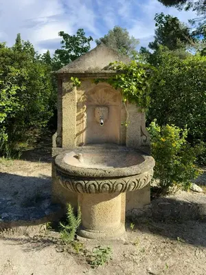 a stone bird bath with a plant on top of it at Au calme dans la campagne Aixoise, entouré de cyprès in Aix-en-Provence