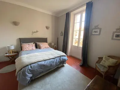 a bedroom with a bed with pink pillows and a window at La Capucine in Cavaillon