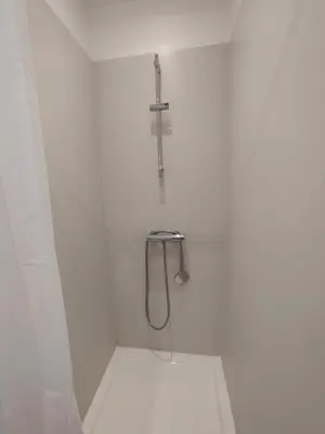 a white bathroom with a shower with a cross on the wall at Le Petit Paradis in Saint-Martin-de-Castillon