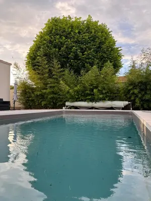 a swimming pool with blue water in a yard at Villa Spacieuse avec Piscine in Entraigues-sur-la-Sorgue
