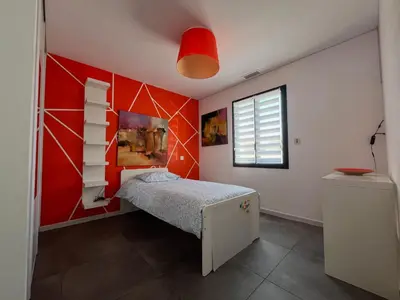 a bedroom with a red accent wall and a bed at Villa Spacieuse avec Piscine in Entraigues-sur-la-Sorgue