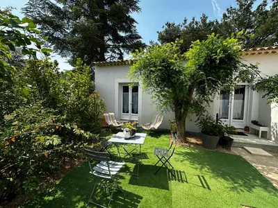 a garden with chairs and a table and a tree at Le refuge des oiseaux in Lourmarin