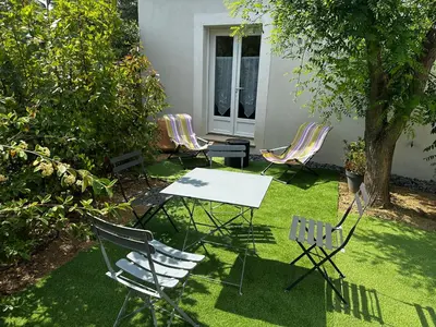 a table and chairs in a yard with grass at Le refuge des oiseaux in Lourmarin