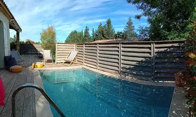 a swimming pool with two chairs next to a fence at Villa Lambesc Provence in Lambesc