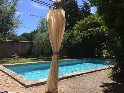 an umbrella in front of a swimming pool at Maison provençale avec piscine in Loriol-du-Comtat