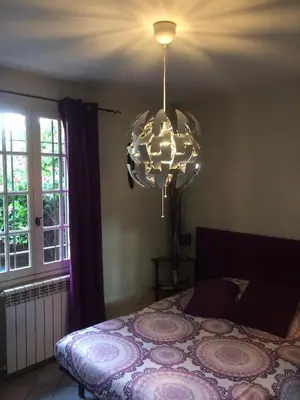 a bedroom with a bed and a chandelier at Maison provençale avec piscine in Loriol-du-Comtat