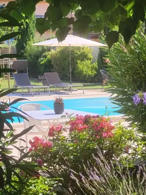 a swimming pool with two chairs and an umbrella at Le Cabanon de Marie in Saignon
