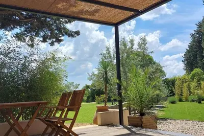 a patio with two wooden chairs and trees at Gîte cosy au coeur du Luberon in Lagnes