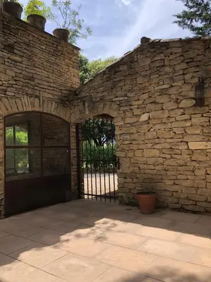an entrance to a stone building with a gate at L'Atelier de la Baronnie - Lubéron in Cabrières-dʼAvignon