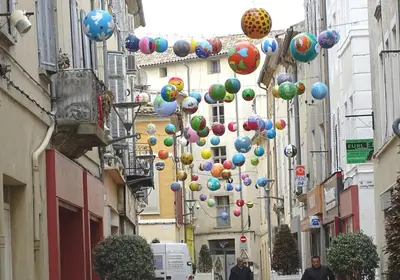 a street with lots of colorful balloons hanging from buildings at Studio centre historique à Carpentras in Carpentras