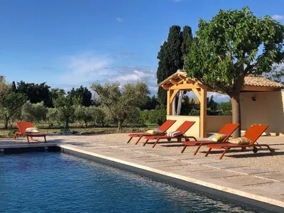 a group of lounge chairs next to a swimming pool at L'Oustalet des Alpilles in Saint-Rémy-de-Provence