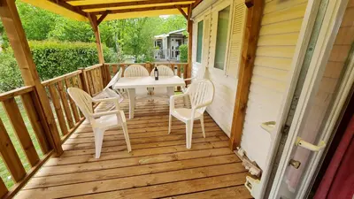 a wooden porch with a table and chairs on it at Mobil Home au calme Camping 4 Cadenet in Cadenet