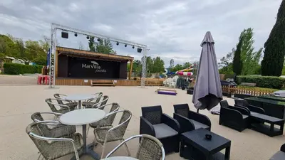 a table and chairs with a stage and an umbrella at Mobil Home au calme Camping 4 Cadenet in Cadenet